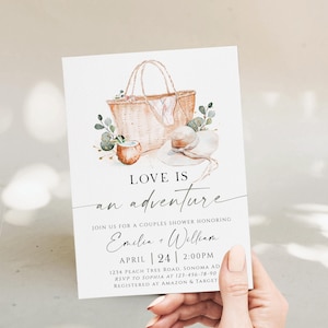 Könnte beinhalten: Eine Einladung zur Babyparty mit einer Aquarellillustration einer Korbtasche, eines Sonnenhuts und Grünzeug. Die Einladung lautet "Love is an adventure" und enthält Eventdetails für Emelia und William.