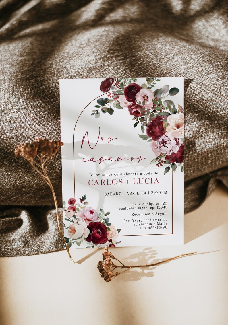 May include: A wedding invitation with a floral design in shades of pink and burgundy. The invitation reads "Nos casamos" which translates to "We are getting married". The invitation also includes the names Carlos and Lucia, the date and time of the wedding, and the address of the ceremony.