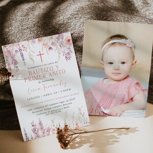 Puede incluir: Una invitaci&oacute;n floral de acuarela para un bautizo y un primer cumplea&ntilde;os. La invitaci&oacute;n presenta una cruz, flores y el texto "Bautizo y Primer Anito" en rosa. El texto "Lucia Fernandez" est&aacute; escrito en cursiva debajo del t&iacute;tulo. La invitaci&oacute;n tambi&eacute;n incluye la fecha, la hora y la ubicaci&oacute;n del evento.