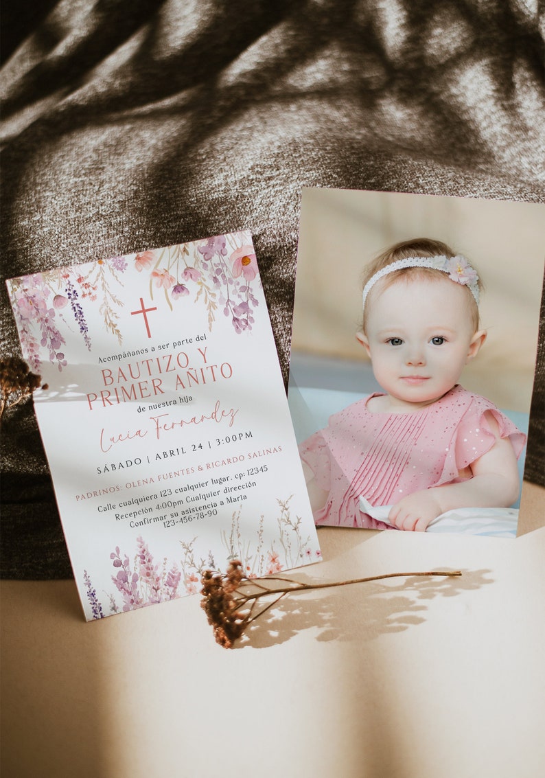 Puede incluir: Una invitaci&oacute;n floral de acuarela para un bautizo y un primer cumplea&ntilde;os. La invitaci&oacute;n presenta una cruz, flores y el texto "Bautizo y Primer Anito" en rosa. El texto "Lucia Fernandez" est&aacute; escrito en cursiva debajo del t&iacute;tulo. La invitaci&oacute;n tambi&eacute;n incluye la fecha, la hora y la ubicaci&oacute;n del evento.