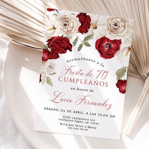 May include: White invitation card with floral design featuring red and white roses. The card reads "Fiesta de 70 Cumpleaños" and includes event details for Lucia Fernandez.