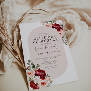 Op de afbeelding: Een witte uitnodigingskaart met bloemaccenten en tekst in het Spaans. De kaart heeft een roze boogontwerp en de woorden "Despedida de Soltera" en "Lucia Fernandez". De datum is 24 april om 15:00 uur.