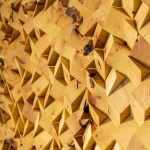 May include: A wall art piece made of wood with a geometric pattern. The wood is a light brown colour and the pattern is made up of squares and triangles.