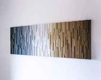 May include: A wall art piece made of wood with a gradient of colors from dark blue to light brown. The wood is arranged in vertical strips of varying lengths, creating a textured and modern look.