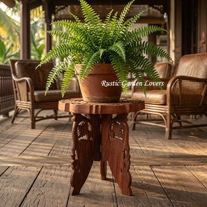 Peut inclure: Un support pour plantes en bois brun avec des pieds sculptés complexes et un plateau rond, soutenant un pot en terre cuite contenant une fougère verte luxuriante. Le texte Rustic Garden Lovers est visible sur le pot. Le support a une base solide.