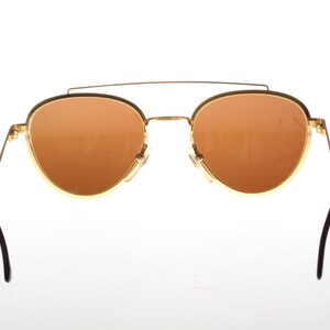 May include: Gold-tone aviator sunglasses with brown lenses and black arms.