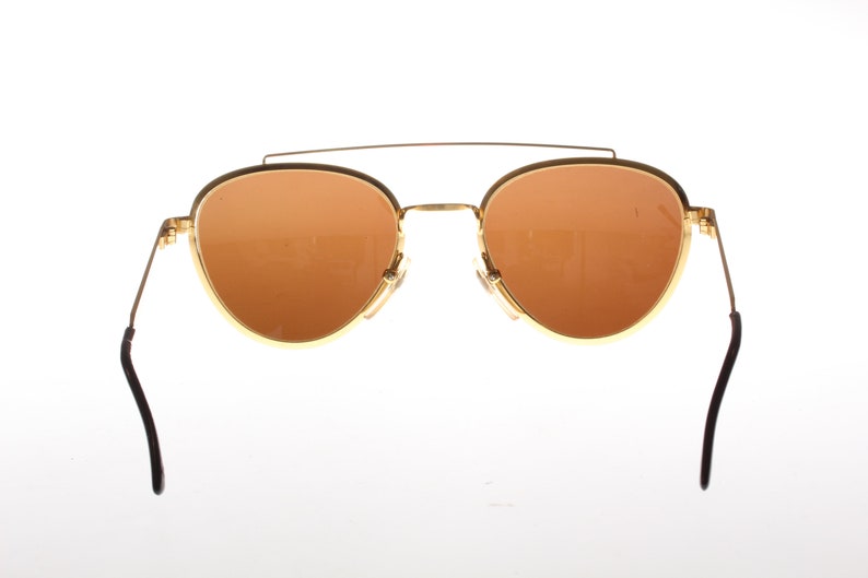May include: Gold-tone aviator sunglasses with brown lenses and black arms.
