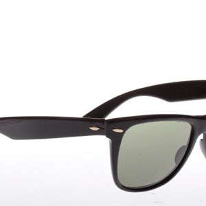 Peut inclure: Lunettes de soleil de style Wayfarer noires avec des verres verts.