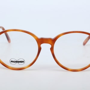 May include: Round tortoiseshell eyeglasses with clear lenses. The brand name "MORWEN" is printed on the right lens.