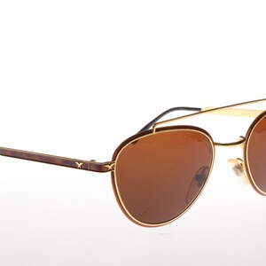 May include: Brown and gold aviator sunglasses with a double bridge and brown lenses.