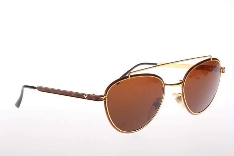 May include: Brown and gold aviator sunglasses with a double bridge and brown lenses.