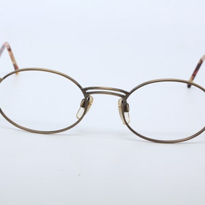 Puede incluir: Un par de gafas redondas de color dorado con patillas de carey.