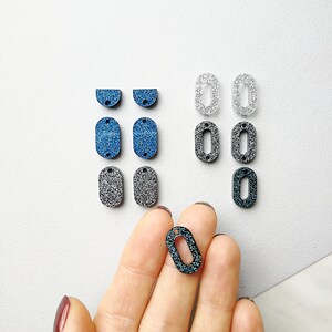 Puede incluir: Surtido de formas ovaladas y semic&iacute;rculos con purpurina y agujeros para manualidades. Las formas son de color azul, plateado y negro.