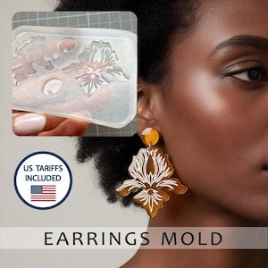 Peut inclure: Un moule à boucles d'oreilles en silicone transparent avec des motifs floraux est tenu dans une main. Une paire de grandes boucles d'oreilles ambrées avec des détails floraux blancs est affichée. Le texte "EARRINGS MOLD" est en bas.