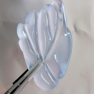 Puede incluir: Un colgante de flor de color azul claro transl&uacute;cido y tallado. La flor tiene un dise&ntilde;o delicado e intrincado con m&uacute;ltiples capas de p&eacute;talos.