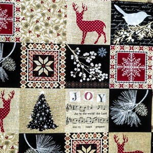 May include: A fabric featuring a patchwork design with red, black, and gold squares. Patterns include polka-dot deer, snowflakes, pinecones, white berries, and a Christmas tree. The text Joy to the world and musical notes are printed on a gold background.