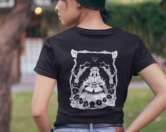 Könnte beinhalten: Schwarzes T-Shirt mit einem weißen Grafikdesign auf dem Rücken. Das Design zeigt eine zentrale Figur, die von verzierten Details umgeben ist. Die Person trägt eine blaue Jeans. Das Bild wird im Freien mit einem verschwommenen Hintergrund aus Bäumen und Gras aufgenommen.