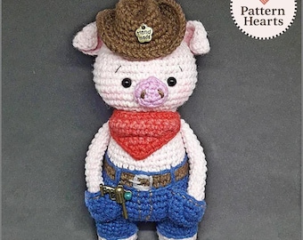 Può includere: Maialino all'uncinetto con cappello da cowboy marrone con bottone "Hand made", bandana rossa, jeans blu e pistola giocattolo. Il maiale ha muso e orecchie rosa. L'oggetto è fatto a mano.