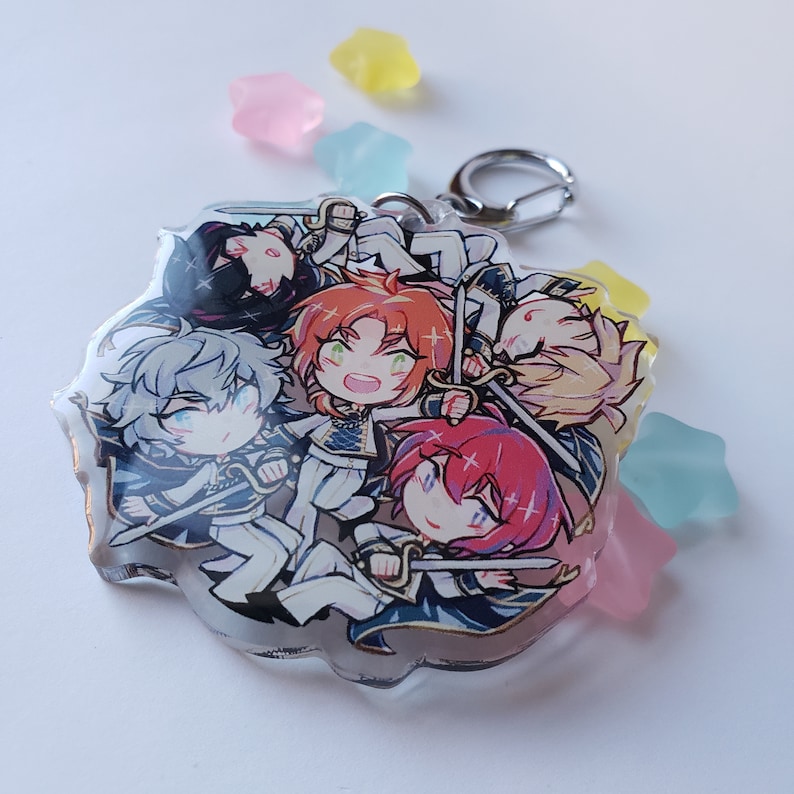 Puede incluir: Un llavero de acr&iacute;lico transparente con cinco personajes de anime con espadas. Los personajes est&aacute;n dibujados en estilo chibi y visten atuendos coloridos. El llavero est&aacute; unido a un anillo de metal plateado.