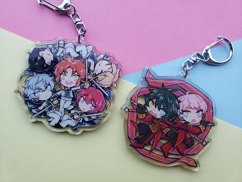 Puede incluir: Dos llaveros de acr&iacute;lico con personajes de estilo anime. El primer llavero tiene cinco personajes en un dise&ntilde;o circular con una cadena plateada. El segundo llavero tiene dos personajes en un dise&ntilde;o rojo y rosa con una cadena plateada.