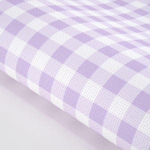 May include: A piece of fabric featuring a repeating gingham pattern in light purple and white. The material has a visible grid-like texture throughout, characterized by alternating solid light purple squares and white squares arranged in a classic check design.