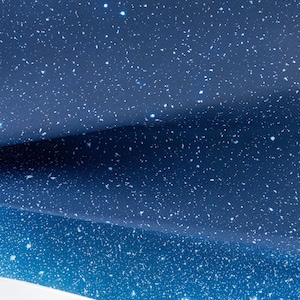 May include: A fabric or paper material featuring a deep blue night sky pattern with scattered white dots representing stars. The surface has a visible texture and is folded to create layers, showing a gradient from dark navy to a lighter blue.
