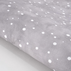 May include: Close-up of a gray fabric with a subtle texture and a pattern of white polka dots. The fabric is folded, revealing its thickness and the interplay of light and shadow across its surface. The dots vary in size.