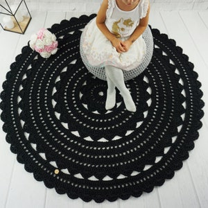 May include: Black crochet round rug with a delicate pattern. The rug is large enough for a child to sit on.