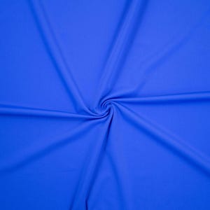 Puede incluir: Primer plano de una tela azul vibrante con una textura suave. La tela está dispuesta en espiral, creando pliegues y sombras que resaltan su textura. El color es un azul rico y sólido, que llena el encuadre.