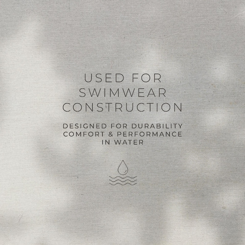 May include: A light gray fabric background featuring dark gray text that reads: USED FOR SWIMWEAR CONSTRUCTION. DESIGNED FOR DURABILITY COMFORT & PERFORMANCE IN WATER. Below the text is a small icon of a single water droplet above three wavy lines.