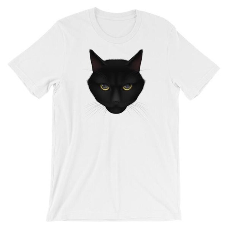 Pu&ograve; includere: Una maglietta bianca con una grafica di un gatto nero. Il gatto ha gli occhi gialli e un'espressione seria.