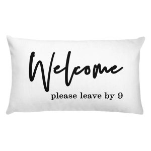 May include: White rectangular pillow with black text that reads "Welcome please leave by 9".