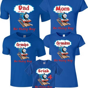 May include: Five blue t-shirts with a Thomas the Tank Engine design. The shirts say "Dad of the Birthday Boy", "Mom of the Birthday Boy", "Grandpa of the Birthday Boy", "Grandma of the Birthday Boy", and "Erick 4 Birthday Boy".