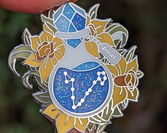 May include: A silver enamel pin featuring a blue glass bottle with a silver lid and a silver tag that says "Pisces". The bottle is filled with blue glitter and a silver outline of the Pisces constellation. The bottle is surrounded by yellow and green floral details.