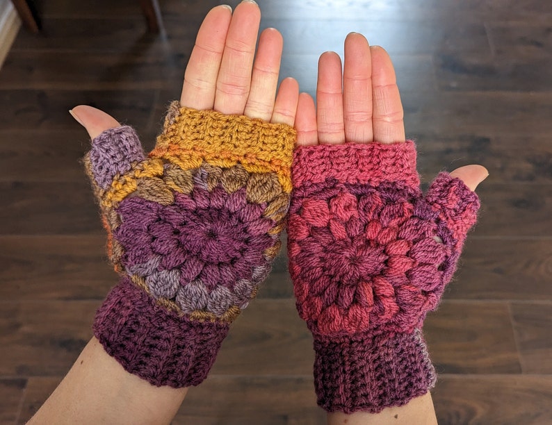 Peut inclure: Une paire de mitaines en crochet avec un motif de granny squares color&eacute;. Les mitaines sont faites avec un m&eacute;lange de fils rose, violet, orange et marron.