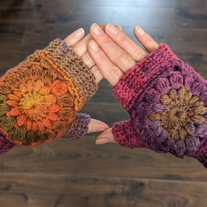 Peut inclure: Une paire de mitaines au crochet avec un motif floral color&eacute;. Les mitaines sont faites avec un d&eacute;grad&eacute; de fils violet, marron, orange et jaune.