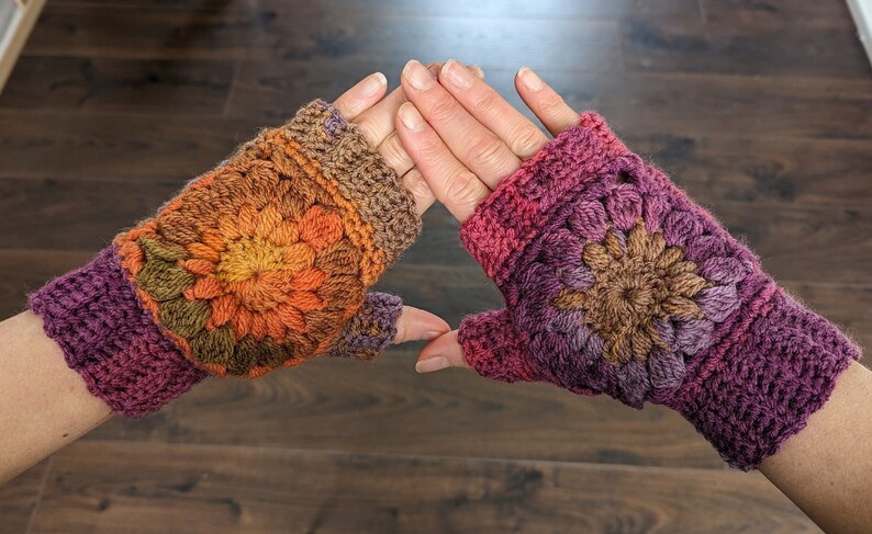 Peut inclure: Une paire de mitaines au crochet avec un motif floral color&eacute;. Les mitaines sont faites avec un d&eacute;grad&eacute; de fils violet, marron, orange et jaune.