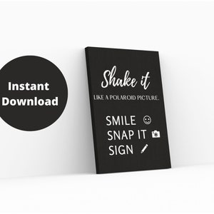 以下が含まれることがあります： 黒いキャンバスプリント。白い文字で「Shake it like a Polaroid picture」と書かれています。下に「Smile, Snap it, Sign」とアイコン。左側に「Instant Download」と書かれた黒い円があります。家の装飾品です。