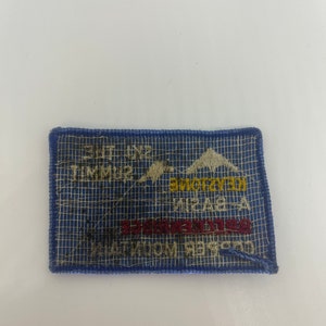 May include: A rectangular blue patch with white text and a mountain graphic. The patch reads "Ski the Summit" and "Keystone" in yellow and red lettering. The patch is bordered with blue stitching.