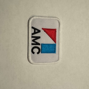 May include: White embroidered patch with the letters "AMC" in black and a red and blue geometric design.