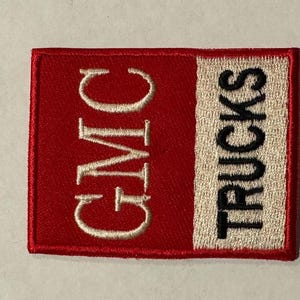 May include: A red and white embroidered patch with the text "GMC TRUCKS" in white and black lettering.