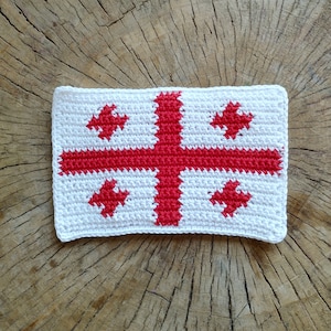 May include: White crocheted square with a red cross and four red crosses in the corners. The cross is a traditional symbol of Georgia.