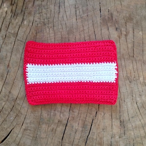 May include: A crocheted red and white flag with a white stripe in the middle.