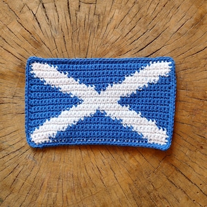 May include: A blue and white crocheted square with a diagonal cross pattern, resembling the Scottish flag.