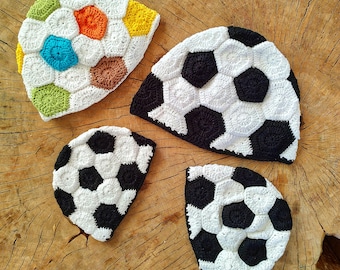 May include: Four crocheted hats in the shape of a soccer ball. One hat is multi-colored with green, brown, yellow, blue, and white. The other three hats are black and white.