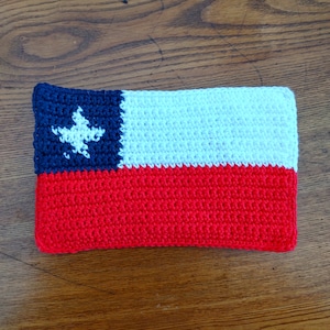 May include: A crocheted Chilean flag in red, white, and blue with a white star on the blue section.