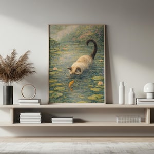 May include: A framed art print depicts a Siamese cat in a pond, reaching for a goldfish. The artwork features lily pads, water reflections, and a soft, impressionistic style. The cat's fur is light brown and cream, with a dark tail.