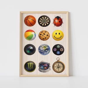 May include: A framed print featuring various colorful images, including a basketball, dartboard, ladybug, beach ball, cookie, smiley face, camera lens, Earth, game controller, Monster energy drink logo, astronaut helmet, and compass.