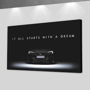 May include: A black canvas print featuring a car with bright headlights and the text "IT ALL STARTS WITH A DREAM" in white. The car is centered and illuminated against a dark background, creating a dramatic effect.