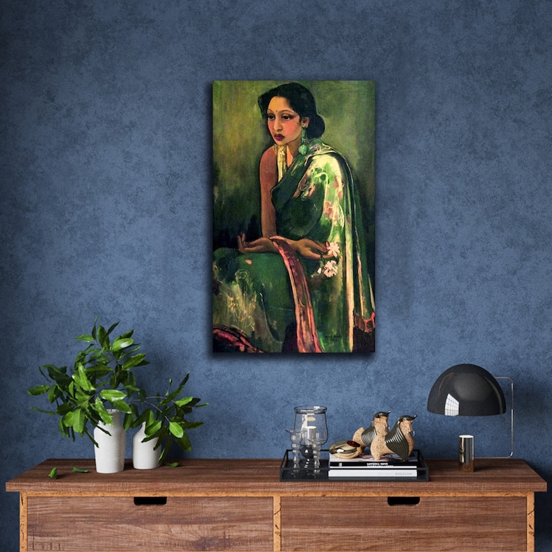 Puede incluir: Una pintura de una mujer que lleva un sari verde y rosa con motivos florales. Est&aacute; sentada con las manos juntas en el regazo y mirando hacia un lado. El fondo es de color verde oscuro.